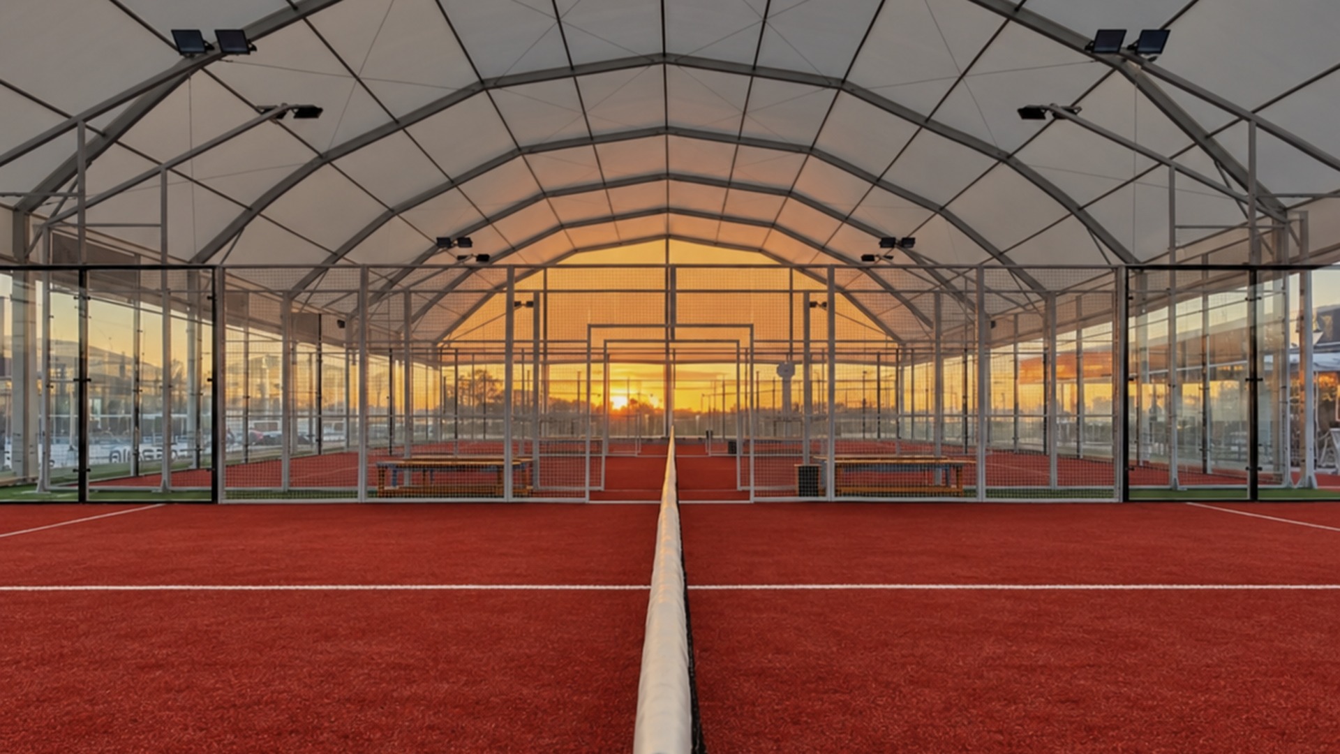 Campos do PurePadel vistos da rede, com o pôr do sol ao fundo